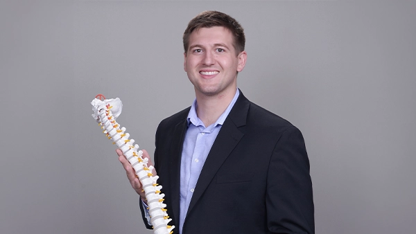 Chiropractor Andrew Plank Holding A Spine Model