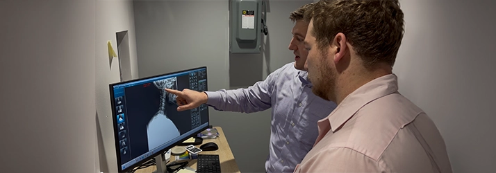Chiropractor Andrew Plank Pointing To A Patients XRay