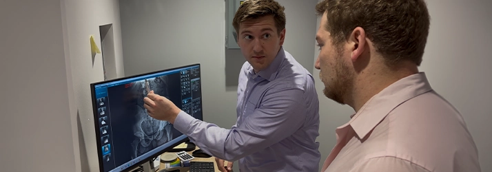 Chiropractor Andrew Plank Pointing To An XRay With Patient